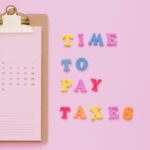 Colorful tax reminder on clipboard against a pink background for March